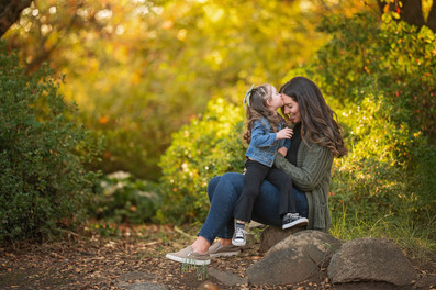 Family with a young child during a fall family photography session surrounded by golden trees at the Iris Farm in Loomis, California.