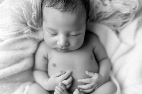 Sweet newborn baby boy peacefully sleeping in a cozy studio setting, wrapped in soft neutrals of cream and white, with delicate details captured like tiny toes, hands, and lashes. Family photos included tender moments with mom and dad. Taken by the best maternity and newborn photographer in Sacramento, Kristina Martin Photography.