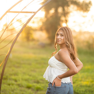 Senior portrait session at a flower farm in Sheridan, California with seasonal flowers, a greenhouse, arches, and warm sunset light.