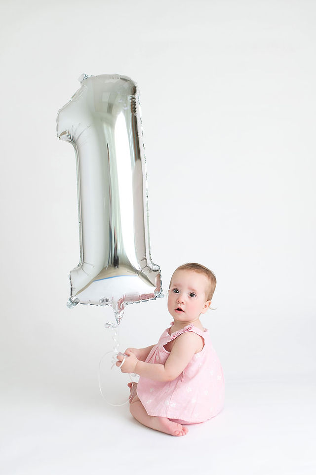 Roseville studio one year milestone session featuring a baby girl, simple white cake smash setup, natural sibling moments, and soft backlit family photography by a Sacramento photographer.
