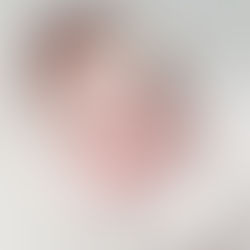 Close-up of a newborn baby girl's face, wearing a white flower headband, with eyes closed, resting on a white knit blanket. Taken by Sacramento maternity and newborn photographer Kristina Martin