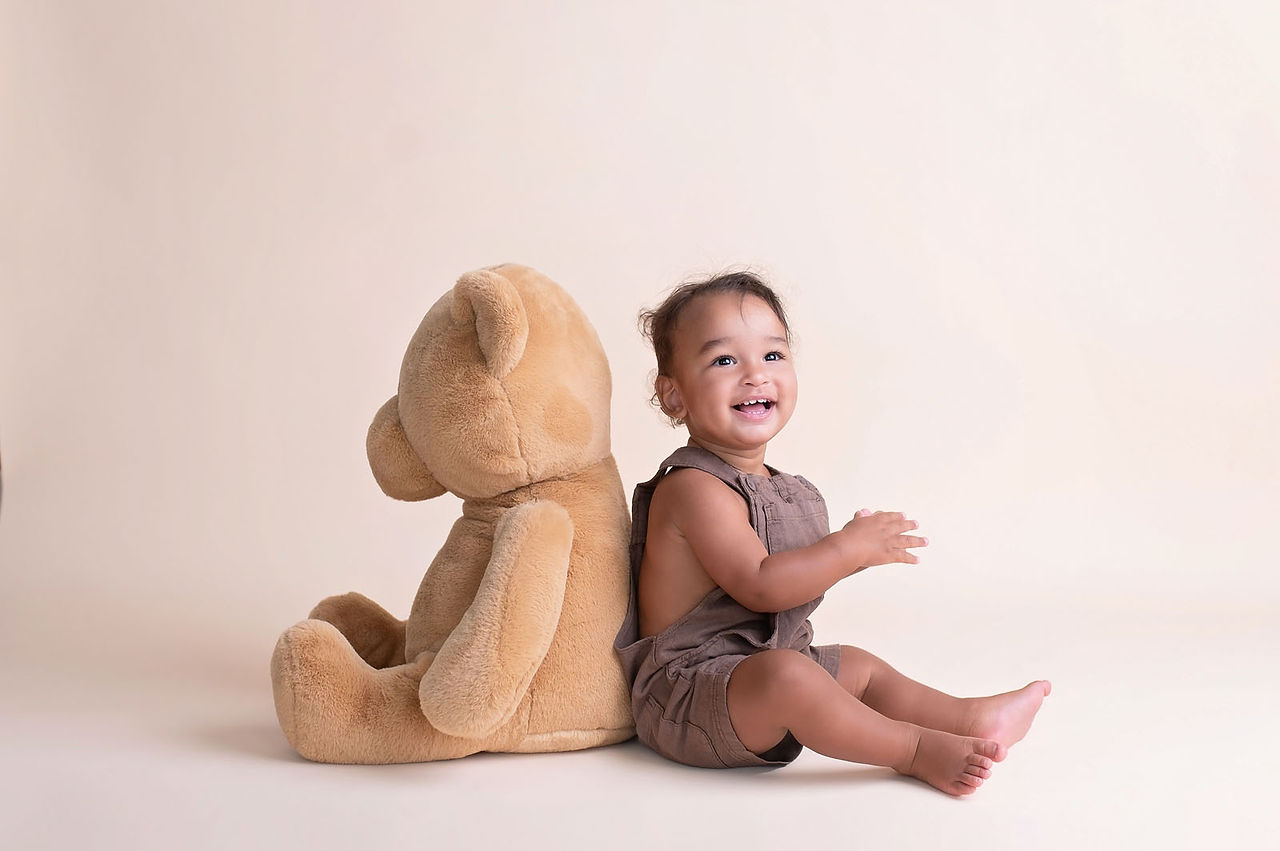 Cake smash session by the best Sacramento photographer featuring a teddy bear theme, neutral balloon arch, and first birthday setup in a studio setting.
