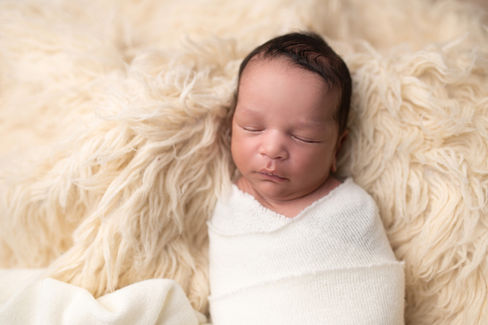 A gallery of newborn session images featuring a swaddled baby in simple, cozy setups. The photos capture a variety of angles, showing the baby peacefully resting in natural, comfortable poses. Some images are taken on a soft white backdrop, while others include a blue background or warm, textured blankets taken by Sacramento Maternity and Newborn photographer Kristina Martin Photography.