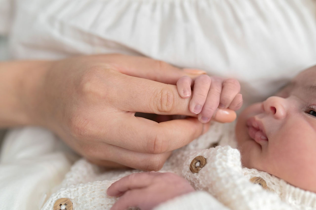 In home Sacramento lifestyle newborn photography session featuring parents and newborn baby in a light, neutral home environment with natural window light and relaxed family interaction.