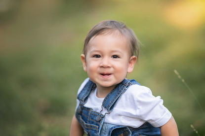 A one-year-old boy celebrating his first birthday with his parents at the Davis Arboretum in Davis, California, finishing the milestone session with a fun cake smash.