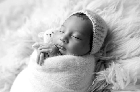 Sweet newborn baby boy peacefully sleeping in a cozy studio setting, wrapped in soft neutrals of cream and white, with delicate details captured like tiny toes, hands, and lashes. Family photos included tender moments with mom and dad. Taken by the best maternity and newborn photographer in Sacramento, Kristina Martin Photography.