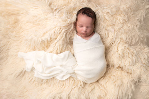 A gallery of newborn session images featuring a swaddled baby in simple, cozy setups. The photos capture a variety of angles, showing the baby peacefully resting in natural, comfortable poses. Some images are taken on a soft white backdrop, while others include a blue background or warm, textured blankets taken by Sacramento Maternity and Newborn photographer Kristina Martin Photography.
