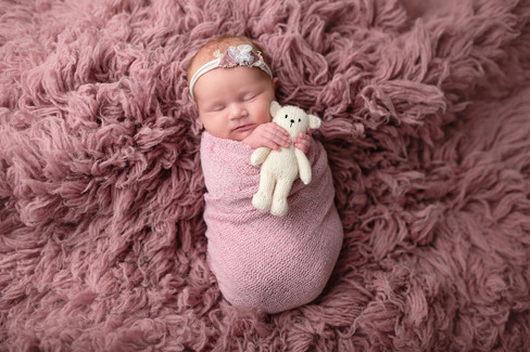 Sacramento newborn photographer capturing a soft in-home newborn session with a baby girl, natural light portraits, neutral wraps, and sweet sibling and family moments.