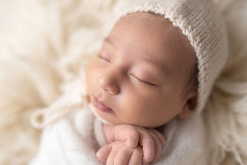 Sweet newborn baby boy peacefully sleeping in a cozy studio setting, wrapped in soft neutrals of cream and white, with delicate details captured like tiny toes, hands, and lashes. Family photos included tender moments with mom and dad. Taken by the best maternity and newborn photographer in Sacramento, Kristina Martin Photography.