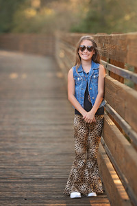 Family photography session at the Citrus Heights Nature Preserve featuring a family walking along a wooden bridge surrounded by trees and warm evening light.