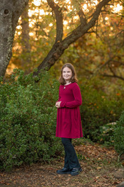 Family of four posing together during a fall family photography session surrounded by golden trees at the Iris Farm in Loomis, California.