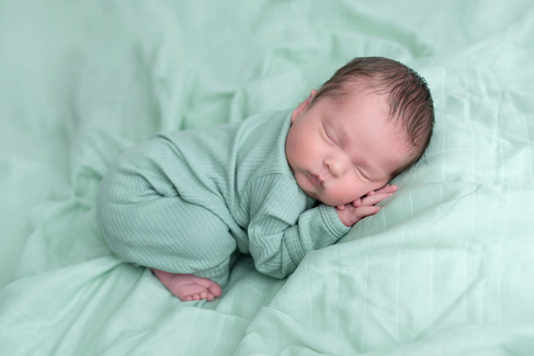 Newborn baby photographed with parents in a neutral studio setting during an in studio newborn session in Roseville, California.