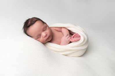 A gallery of newborn session images featuring a swaddled baby in simple, cozy setups. The photos capture a variety of angles, showing the baby peacefully resting in natural, comfortable poses. Some images are taken on a soft white backdrop, while others include a blue background or warm, textured blankets taken by Sacramento Maternity and Newborn photographer Kristina Martin Photography.