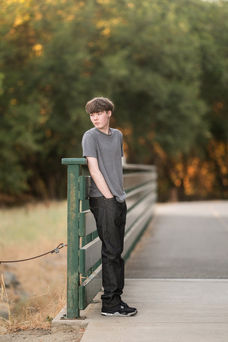 Izzack poses in an open field during sunset, capturing the golden light as it shines through the grass. Shot by the best Sacramento senior photographer.