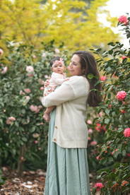 Family session at a blooming botanical garden in Sacramento featuring parents with their three month old baby girl, soft floral backdrops, candid moments, and natural light photography by a local Sacramento baby and family photographer.