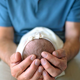 Father holding newborn baby girl in his hands, cradling her head gently. Taken by Sacramento maternity and newborn photographer Kristina Martin