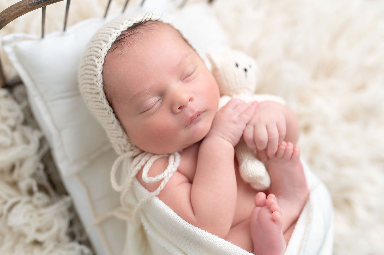 Newborn baby photographed with parents in a neutral studio setting during an in studio newborn session in Roseville, California.