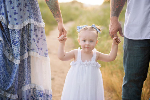 Sacramento family photographer capturing a golden hour wildflower family session in Roseville with a two year old toddler, open fields, and natural family moments.
