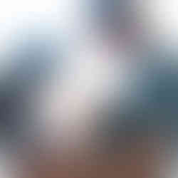 Parents standing by a window, looking down lovingly at their newborn baby girl, with sunlight streaming in behind them. Beautifully backlit family picture. Taken by Sacramento maternity and newborn photographer Kristina Martin