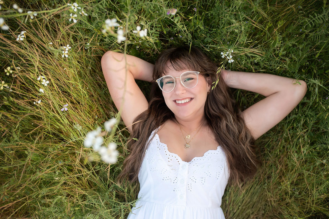 Senior girl in wildflower field at sunset, laughing and smiling during a golden hour photo session with the best Sacramento senior photographer.