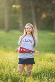 High school senior girl posing in a blooming botanical garden in Sacramento during spring, wearing multiple outfits including a navy dress, a soft pink dress, and college gear, captured in golden hour light by a Sacramento senior photographer.