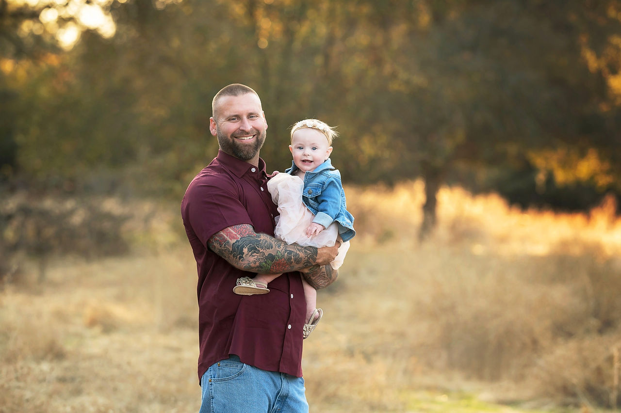 Sacramento family photographer captures a family of three in a local park at sunset with golden dry grass and warm natural tones.