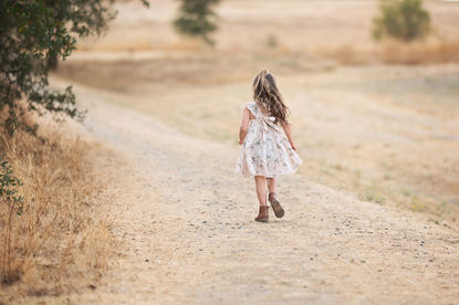 A beautiful maternity photography session taken by the best Sacramento maternity photographer, featuring a glowing mother-to-be in stunning settings. The images showcase a mix of posed and candid moments with her family, including her partner and children, set against rustic barns, lush greenery, and serene sunset backdrops. The session highlights elegant maternity gowns in shades of blue and pink, capturing the joy, love, and anticipation of this special time.