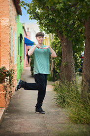 Izzack stands among vibrant, colorful cottages near Capitola Beach, showcasing the charm of the seaside town. Shot by the best Sacramento senior photographer.