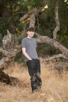 Izzack poses in an open field during sunset, capturing the golden light as it shines through the grass. Shot by the best Sacramento senior photographer.