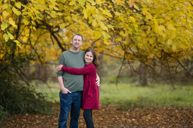 Family of four posing together during a fall family photography session surrounded by golden trees at the Iris Farm in Loomis, California.