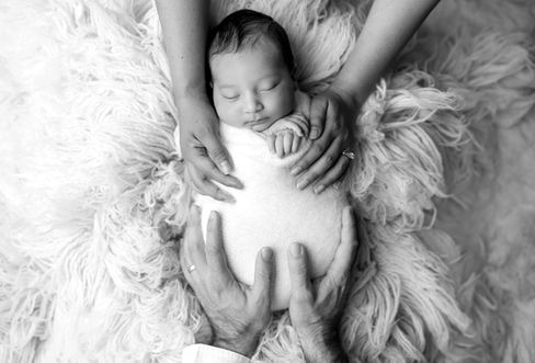 Sweet newborn baby boy peacefully sleeping in a cozy studio setting, wrapped in soft neutrals of cream and white, with delicate details captured like tiny toes, hands, and lashes. Family photos included tender moments with mom and dad. Taken by the best maternity and newborn photographer in Sacramento, Kristina Martin Photography.