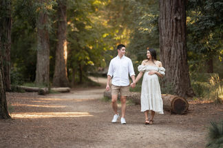 Couple walking and holding belly during maternity session in the forest by best Sacramento maternity photographer Kristina Martin