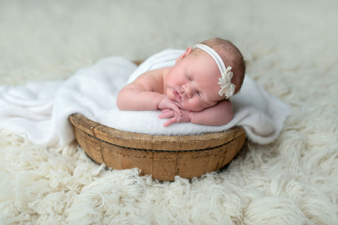 Sacramento newborn photographer capturing a soft in-home newborn session with a baby girl, natural light portraits, neutral wraps, and sweet sibling and family moments.