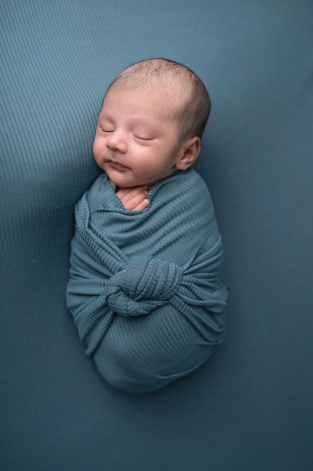 Newborn baby wrapped in soft neutral blankets during an in-home newborn photography session by Sacramento newborn photographer Kristina Martin.