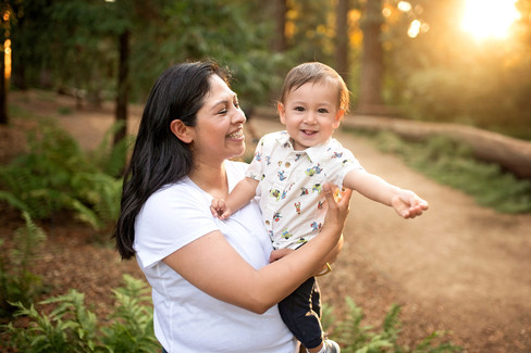 A one-year-old boy celebrating his first birthday with his parents at the Davis Arboretum in Davis, California, finishing the milestone session with a fun cake smash.