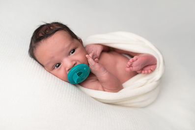 A gallery of newborn session images featuring a swaddled baby in simple, cozy setups. The photos capture a variety of angles, showing the baby peacefully resting in natural, comfortable poses. Some images are taken on a soft white backdrop, while others include a blue background or warm, textured blankets taken by Sacramento Maternity and Newborn photographer Kristina Martin Photography.