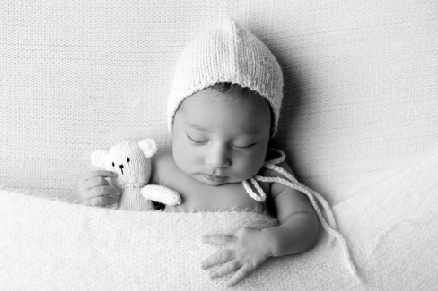 Sweet newborn baby boy peacefully sleeping in a cozy studio setting, wrapped in soft neutrals of cream and white, with delicate details captured like tiny toes, hands, and lashes. Family photos included tender moments with mom and dad. Taken by the best maternity and newborn photographer in Sacramento, Kristina Martin Photography.