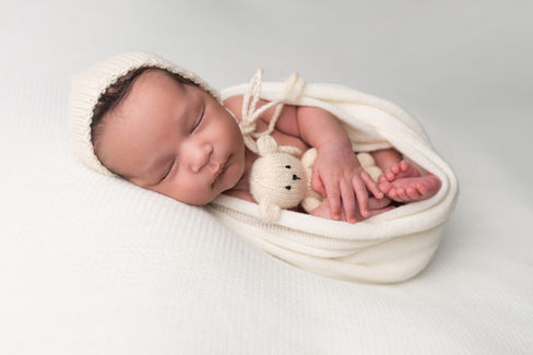 A gallery of newborn session images featuring a swaddled baby in simple, cozy setups. The photos capture a variety of angles, showing the baby peacefully resting in natural, comfortable poses. Some images are taken on a soft white backdrop, while others include a blue background or warm, textured blankets taken by Sacramento Maternity and Newborn photographer Kristina Martin Photography.