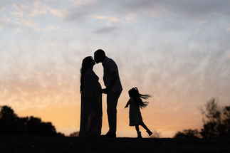 Silhouette of a pregnant mother and young daughter sharing a kiss at sunset, photographed by the best Sacramento maternity photographer, Kristina Martin.
