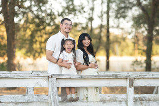 Family of three standing together on a white bridge, symbolizing the unity and anticipation for the new family member, photographed by the best Sacramento maternity photographer.