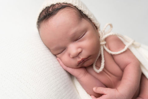 A gallery of newborn session images featuring a swaddled baby in simple, cozy setups. The photos capture a variety of angles, showing the baby peacefully resting in natural, comfortable poses. Some images are taken on a soft white backdrop, while others include a blue background or warm, textured blankets taken by Sacramento Maternity and Newborn photographer Kristina Martin Photography.