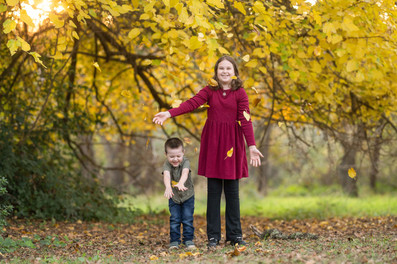 Family of four posing together during a fall family photography session surrounded by golden trees at the Iris Farm in Loomis, California.