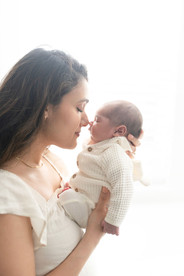 In home Sacramento lifestyle newborn photography session featuring parents and newborn baby in a light, neutral home environment with natural window light and relaxed family interaction.