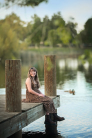Senior girl in wildflower field at sunset, laughing and smiling during a golden hour photo session with the best Sacramento senior photographer.