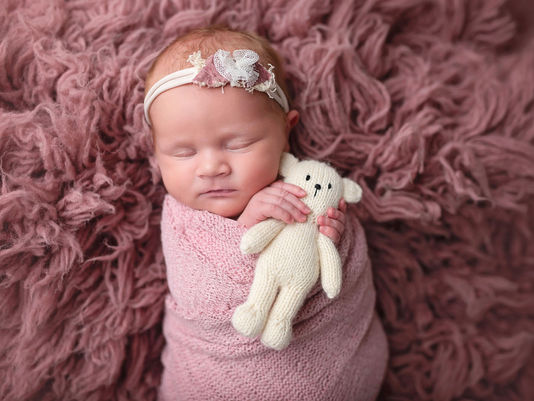 Sacramento newborn photographer capturing a soft in-home newborn session with a baby girl, natural light portraits, neutral wraps, and sweet sibling and family moments.