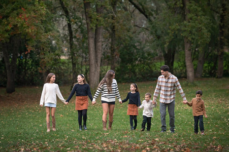 Large extended family posing together among golden fall trees during a family photography session at the Iris Farm in Loomis, California.