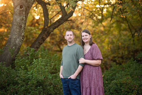 Family of four posing together during a fall family photography session surrounded by golden trees at the Iris Farm in Loomis, California.