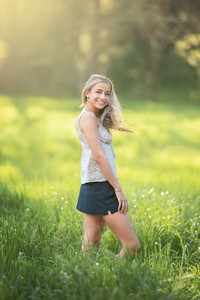 High school senior girl posing in a blooming botanical garden in Sacramento during spring, wearing multiple outfits including a navy dress, a soft pink dress, and college gear, captured in golden hour light by a Sacramento senior photographer.