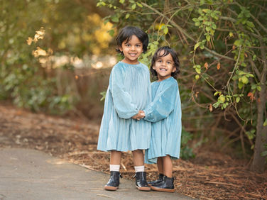 Family walking together at the Davis Arboretum during a fall photo session with their two young daughters and dogs, surrounded by warm golden light and trees.
