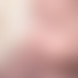 Close-up macro of a newborn baby girl's face, wrapped in a light pink knitted outfit, with eyes closed in sleep. Focus falls on the delicate eyelashes. Taken by Sacramento maternity and newborn photographer Kristina Martin